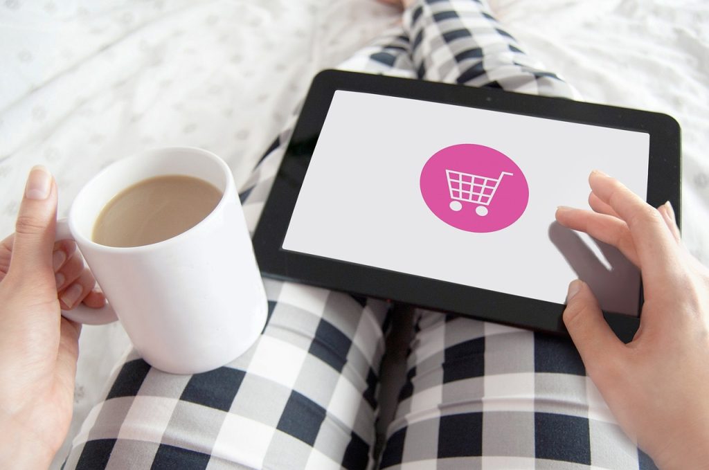 Tablet on lap with person holding a coffee, while shopping online