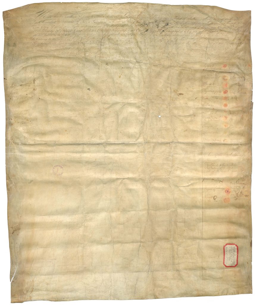 A wrinkled, yellow piece of parchment with a small, red rectangle in the lower right hand corner
