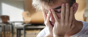 A student is holding their head in their hands because they don't feel well.