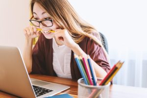 A woman looks stressed while working on laptop.