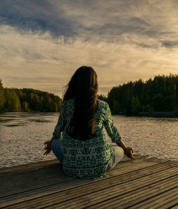 A person is meditating on a dock.