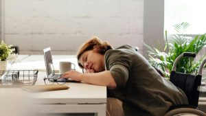 A student has fallen asleep at their desk while working on their laptop.