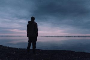A person staring at a peacful lake.