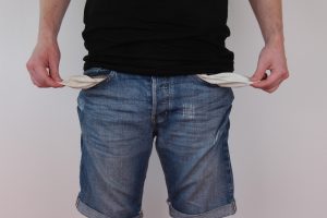 A person showing that their pockets are empty by pulling them inside out.