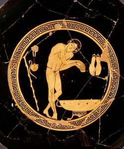 Interior medallion of a red figure kylix depicting a nude male athlete bathing at a wash-basin. Hanging on the wall on either side of the athlete is an aryballos (left) and sandals (right).