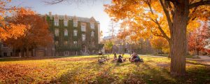 Students sitting on a greenspace at McMaster campus in Fall.