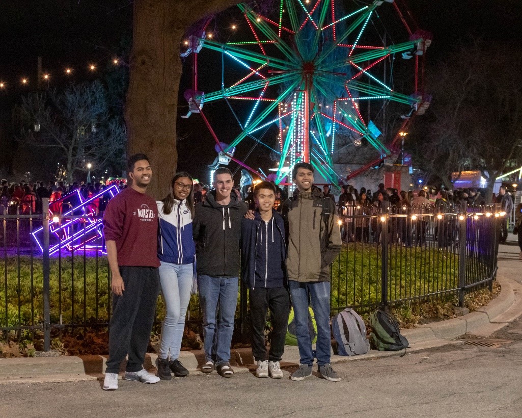 Five students posing in front of a ferris wheel at McMaster campus.