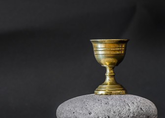 A golden chalice sitting on a rock. Drink from this chalice in celebration of completing your thesis.