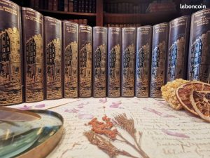 Collection de volumes reliés des œuvres complètes d’Émile Zola, alignés sur une table.