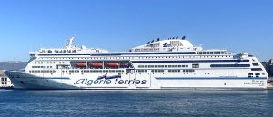 Traversier de la compagnie Algérie Ferries, blanc, amarré au port, sous un ciel bleu.