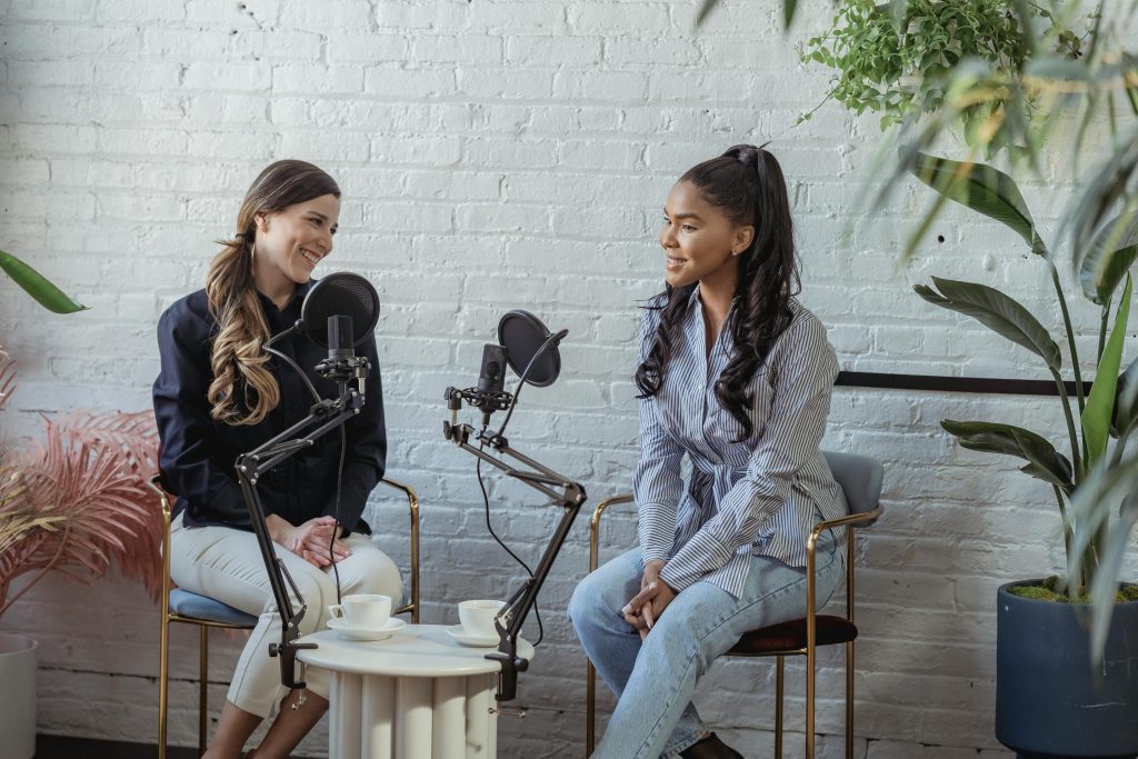 Two women conversing in front of a microphone