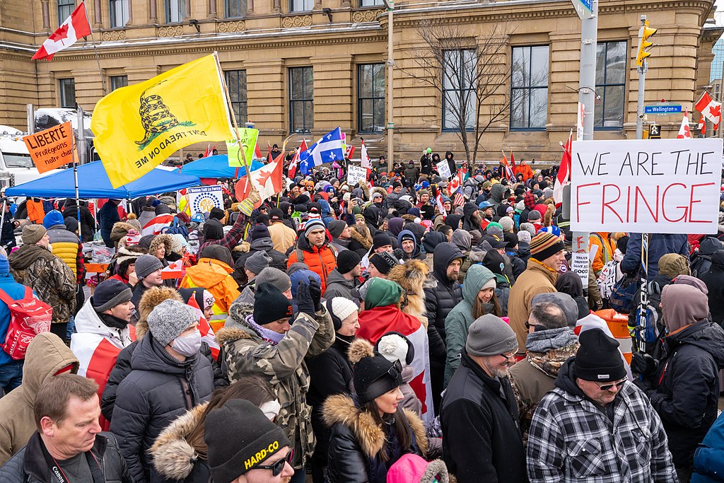 Protestors at the "Freedom Convoy" 2022, Ottawa, Canada. The crowd is all white, waving Canadian and Quebec flags, and a prominent sign reads, "We are the fringe."