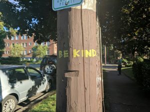 Telephone pole with the words "Be Kind" written on its front.