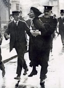 A woman being carried by a police office.