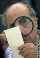 A judge examines a punch card ballot for signs of a hanging chad.