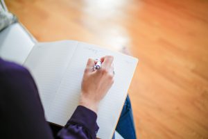 A photo of a person writing in a notebook.