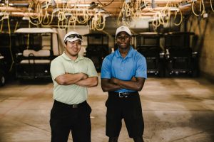 two men crossing their arms while standing near golf carts