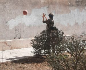 A person bouncing a ball off a wall.