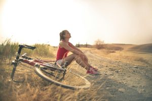 A person taking a break from biking and enjoying the fresh air and sunshine along a path.