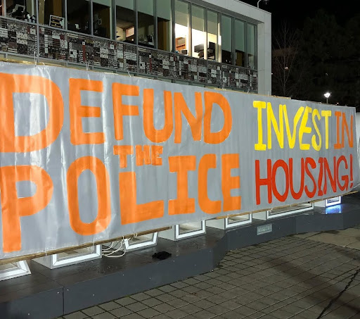 A banner with the words "Defund the police and Invest in Housing."