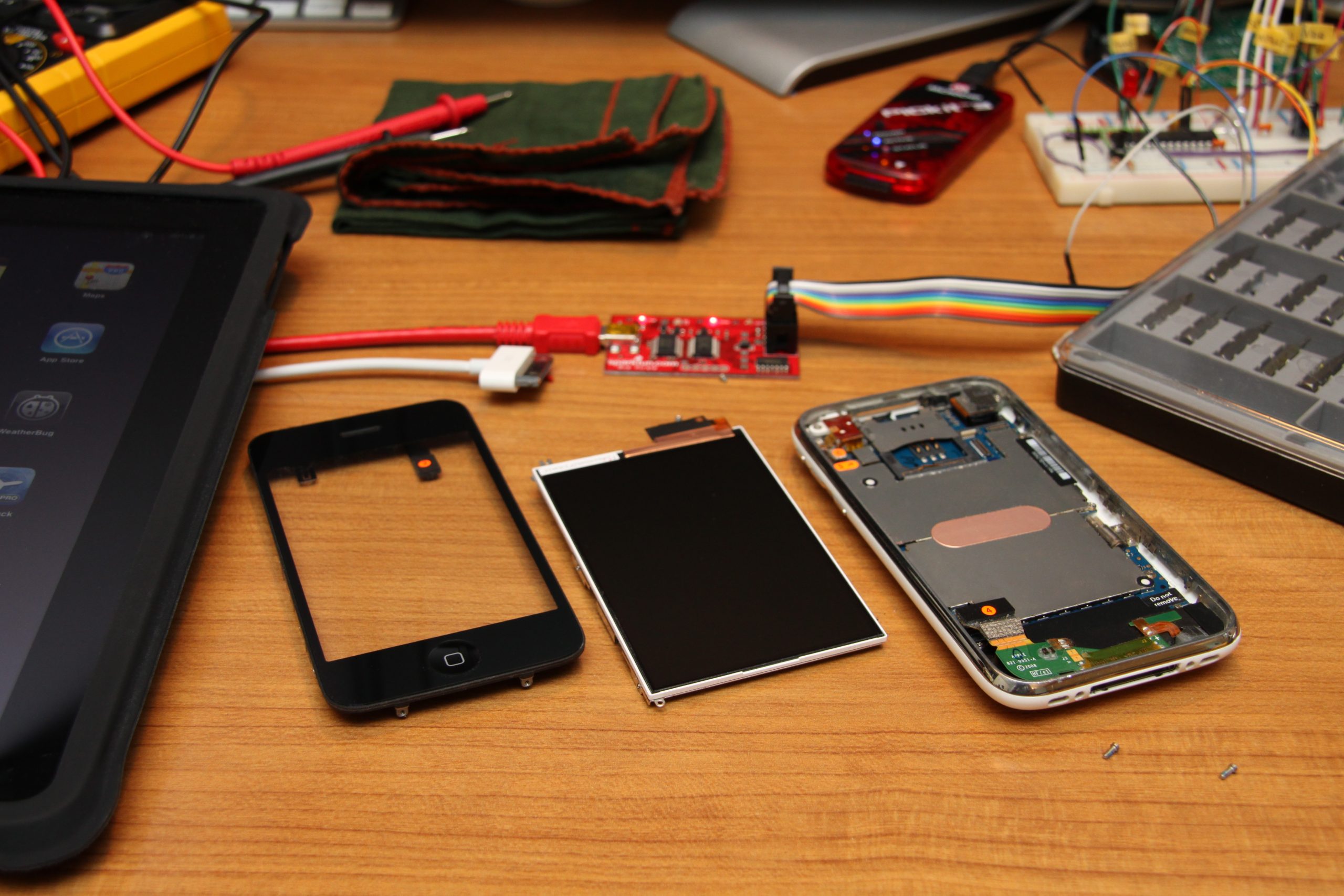 An iPhone taken apart and separated into about ten parts. Visible are the battery, the haptic engine, the camera, and the larger frames.