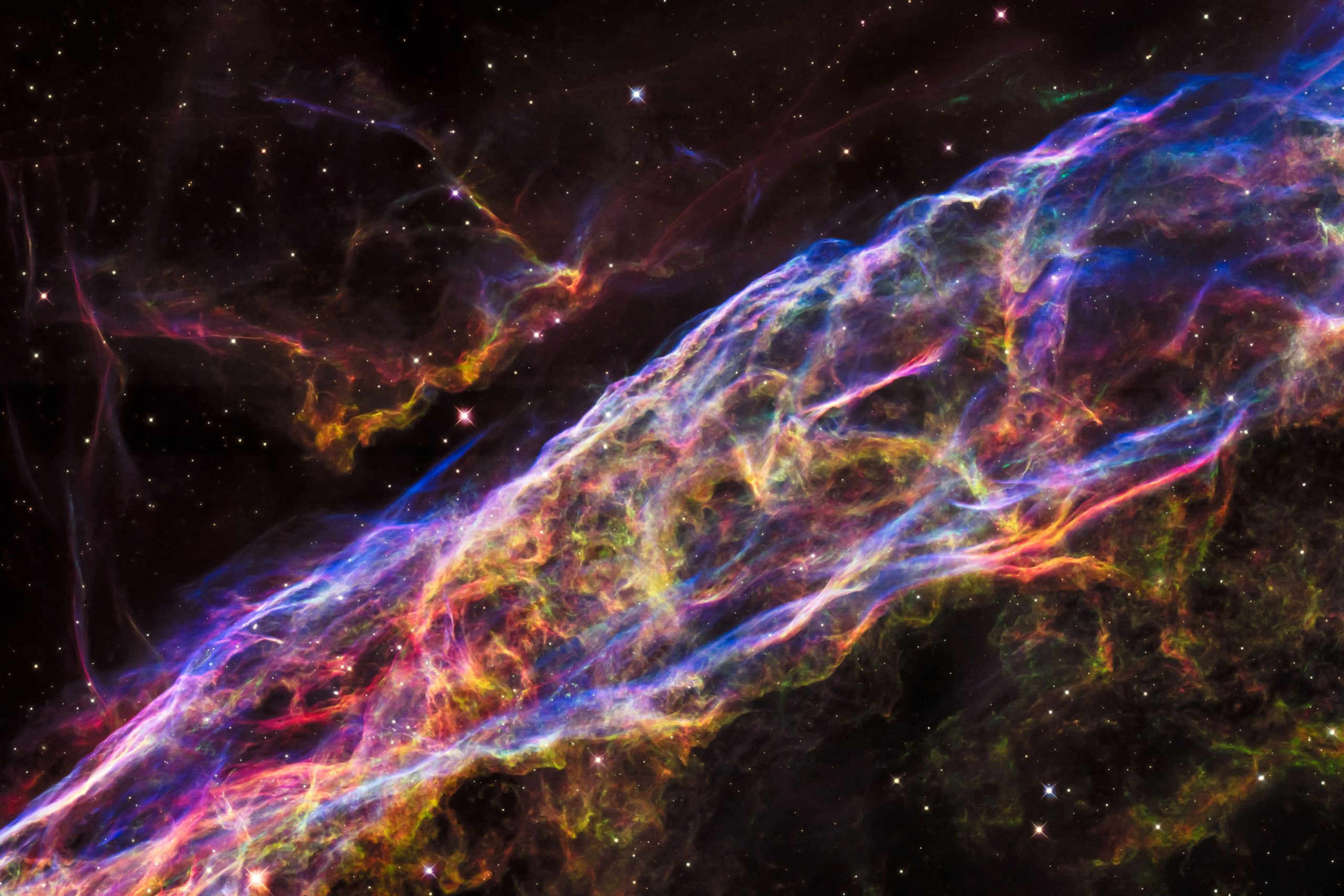 A filament of gas resembles an enormous bubble or surface stretching across the entire image. Stars and smaller gas filaments are also visible in the background.
