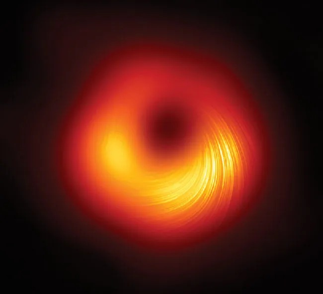 A roughly circular glowing object surrounds a smaller and much darker region. Toward the bottom of the image is a series of several dozen concentric brighter lines.