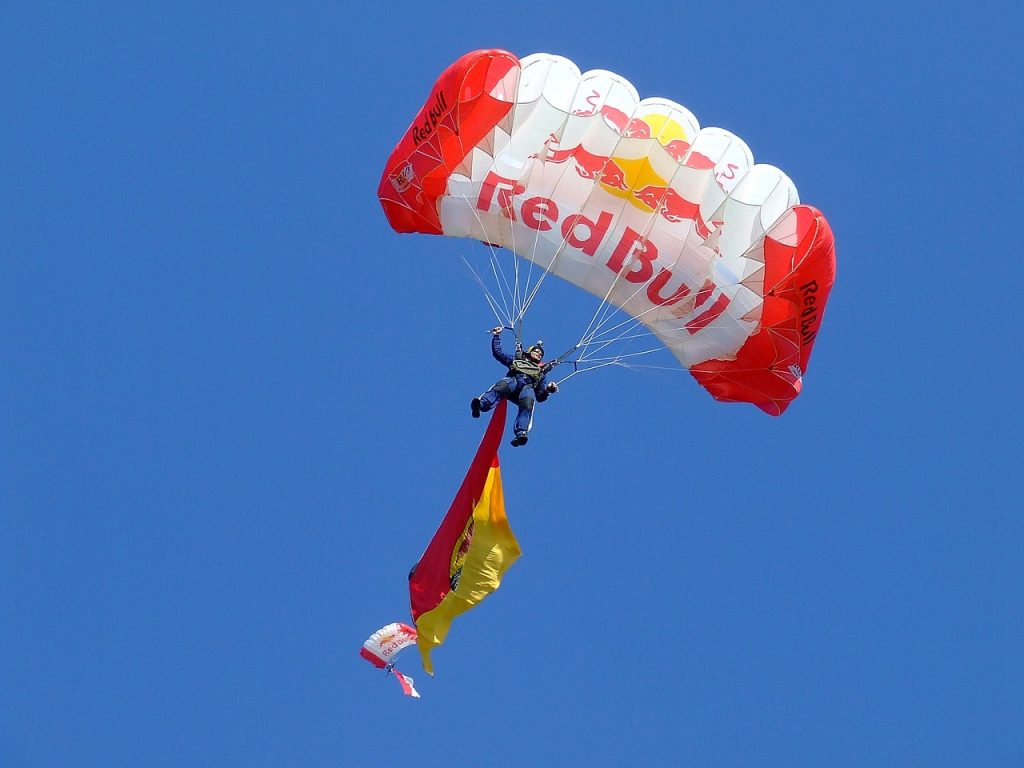 Person in blue sky with Red Bull logo and wordmark on parachute
