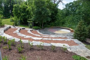 An Indigenous circle set in front of a group of trees, surrounded by semi circle of large rocks to resemble stadium seating.