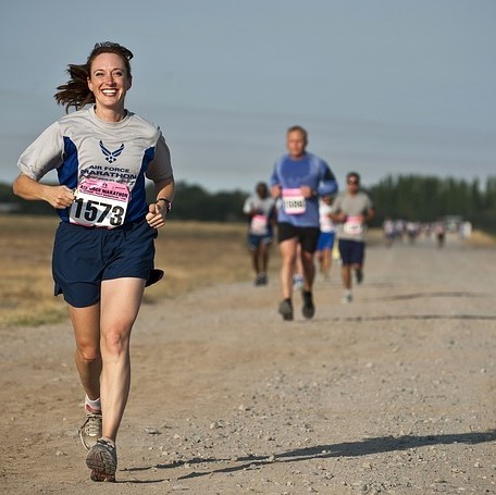 Photo of a people running on a dirt road wearing race bibs