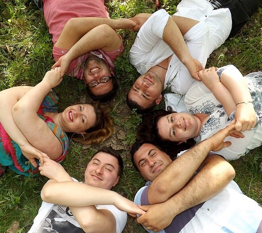 people laying on grass with heads forming a circle holding hands