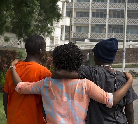 photo of three people from the back with their arms around eachother