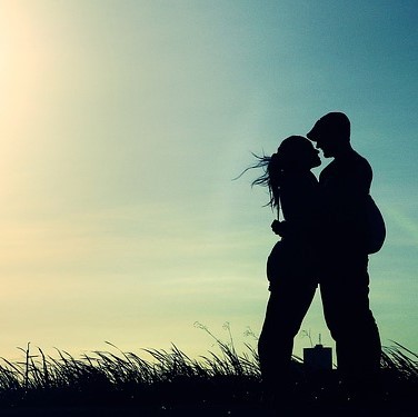 photo of two people standing in tall grass silhouetted holding each other closely