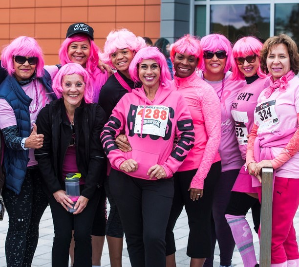 photo of group of people posing wearing all pink and pink wigs wearing race bibs