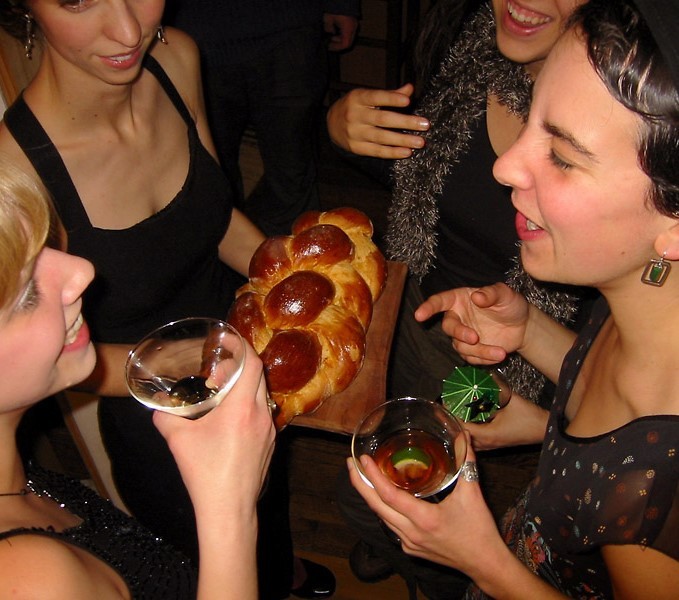 4 females holding drinks and eating pizza