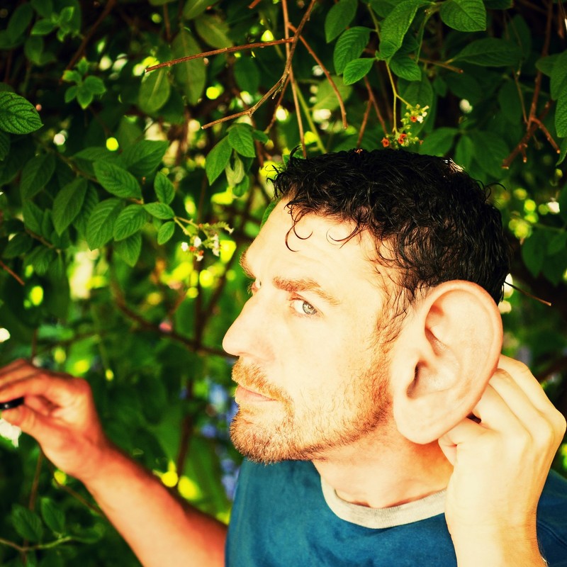 photo of man turning head to listen. Man's ear is photoshopped to look muhc bigger