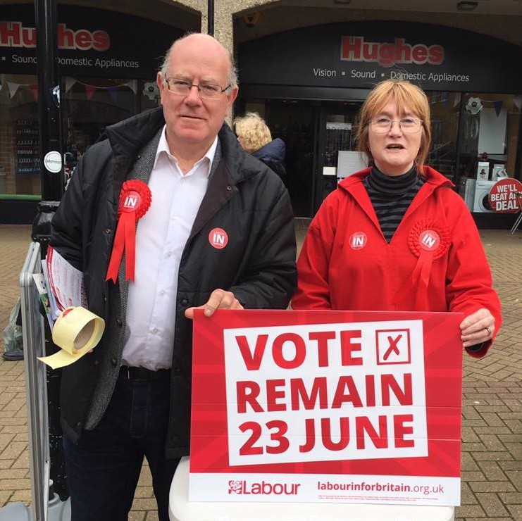 two people standing outside holding a sign