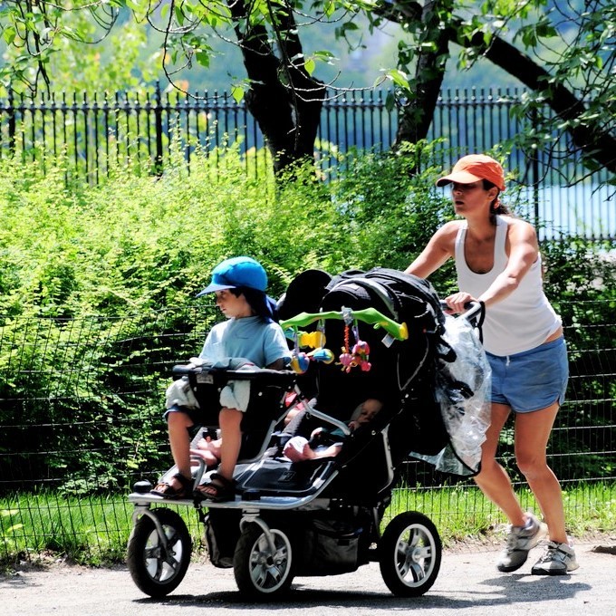 photo of a woman pushing a stroller in a park