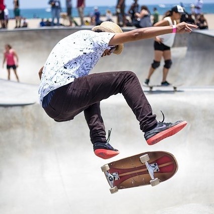 photo of a person doing a kick flip on a skateboard at a skate park 