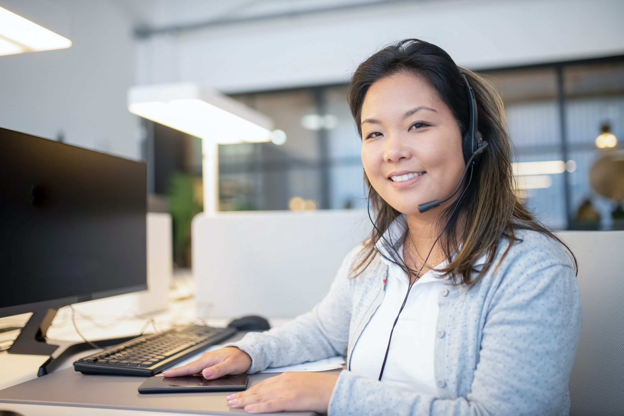 Customer service agent sitting at computer with headset