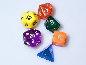 Six polyhedral dice: one blue d4, one orange d6, one green d8, one red d10, one yellow d12, and one purple d20