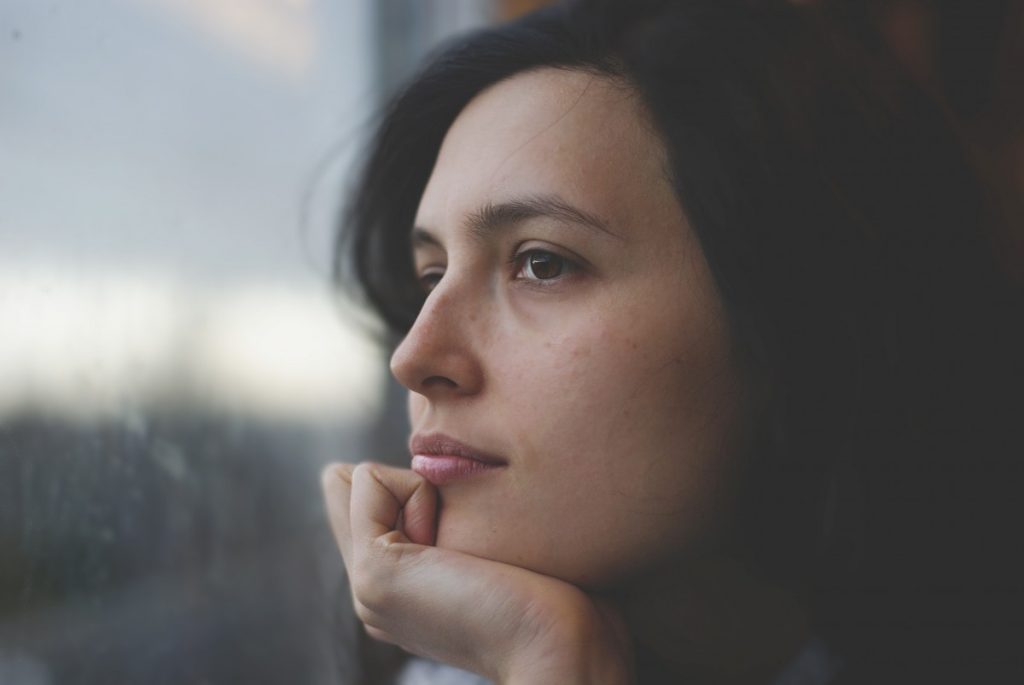 woman staring off into window with hand on chin