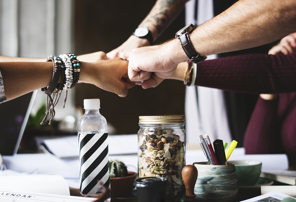 five people putting their fists together over a table