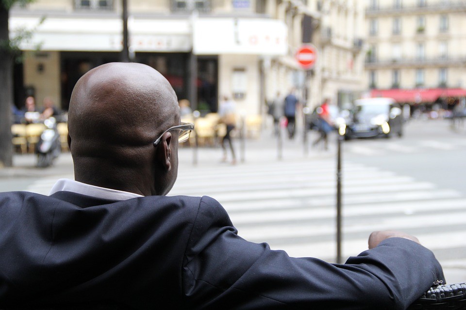 man sitting on bench looking at a street