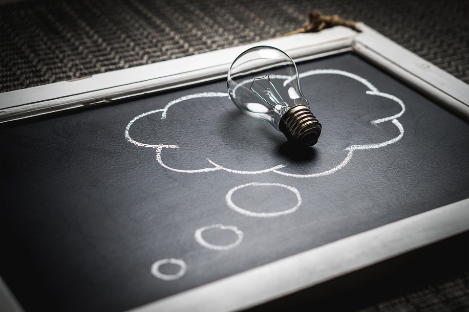 a lightbulb inside of a thought bubble on a chalkboard