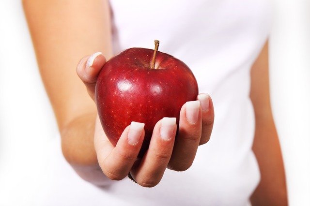 A woman holds an apple in her hand.