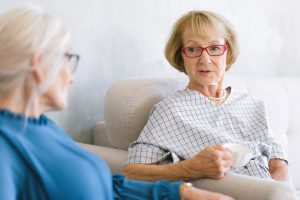 Two senior women are chatting while drinking tea.