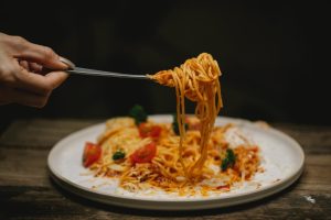 Someone lifts a fork full of spaghetti from a plate
