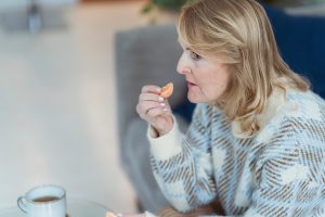 A senior woman is about to eat a piece of orange.