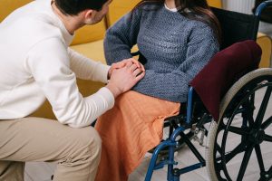 A man clasps hands with a woman in a wheelchair.